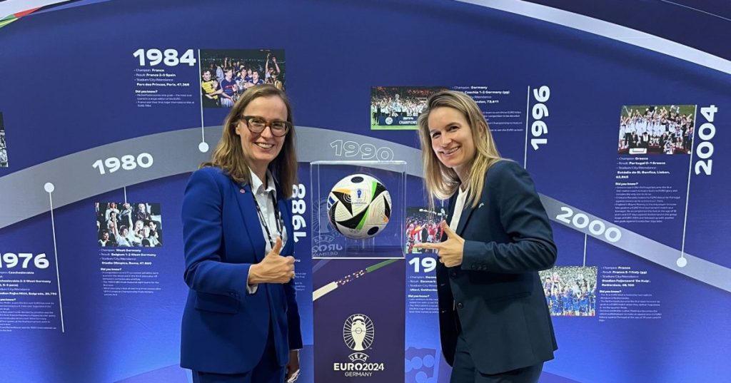 Two women posing next to the Euro 2024 match ball